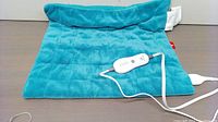 Full view of teal blue plush weighted electric heating pad showing the texture and size of the pad and attached controller controller wired to the pad.