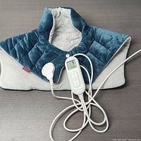 Full view of the electric heating pad draped over a surface with the remote controller connected and visible.