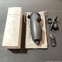 Complete lot showing 2-in-1 black air pump, three inflation nozzles, USB charging cable, light fabric storage bag, and the product box on a surface.