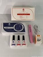 Full kit with box, UV LED lamp, nail polishes, nail tips pack, nail file, and charging cable laid out on table.