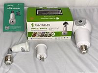 Symynelec Smart Camera, user manual, and two adapters displayed alongside the box.