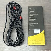 Black braided HDMI cable coiled next to black and yellow packaging box with multilingual instructions visible.