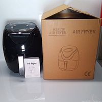 Black RHSTAO MK-08A air fryer displayed next to its original cardboard box showing printed air fryer image and text.