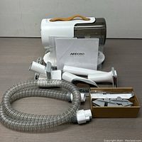 Full lot showing the main Airobo pet grooming vacuum unit, flexible hose, multiple grooming attachments, and a user manual.