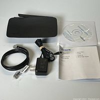 Router with power adapter, Ethernet cable, setup CD, and quick start guide showing included items in the lot.