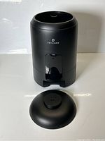 Black Petlibro automatic pet feeder with detached lid on a white surface.