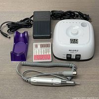Full set including control unit, foot pedal, handpiece, drill bits, and stand arranged on flat surface.