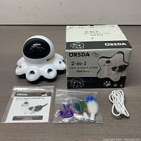 Complete lot showing the octopus-shaped 2-in-1 cat toy, USB cable, instruction manual and feathered cat toy attachments on a table.