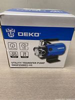Box front showing Deko Utility Transfer Pump DKGP250R01-US with logo and specs of 330 GPH, 1/10 HP, 26 FT head, 120V 60Hz.