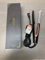 Photo shows Dorisilk hair straightener next to its original box, placed on a wooden surface.