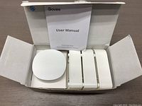 Opened box showing three water detector sensors and round WiFi gateway with user manual in white packaging.