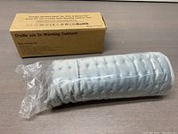 Heating pad rolled up in plastic along with the product box.