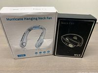 Two boxed neck fans: white Hurricane Hanging Neck Fan J18 and black Neck Fan M15