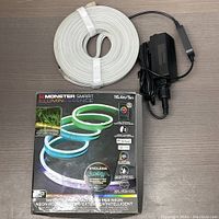 Coiled Monster Illuminescence Smart LED Strip with box and power adapter on a dark surface.