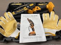 Set including Angseen electric mini chainsaw, pair of yellow/white gloves, carrying case, and operation manual laid out on wooden surface.