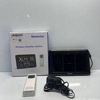 Photo of the Newentor Wireless Weather Station set including the main display unit, outdoor sensor, power cable, and product box.