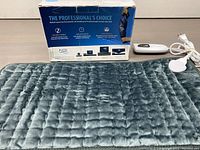 Full view of heating pad in front of original box with controller and power cord visible