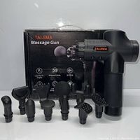 Taijima massage gun with 10 different massage attachments displayed in front of the original box with product features.