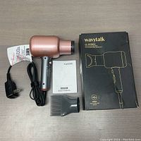 Wavytalk hair dryer with power cord, concentrator nozzle attachment, user manual, and original box on light wood surface.