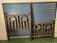 Full view of the antique brass headboard, footboard, and bedrails arranged against a blue metal door.