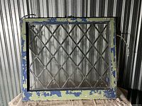 Front view of antique leaded glass window showing diamond leaded pattern and distressed blue and green painted frame.