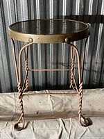 Front view of antique vanity stool showing twisted steel legs and metal seat with rivet trim.