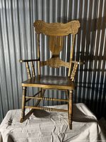 Front and side view of the antique wooden rocking chair showing the overall build and design.