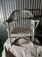 Front view of antique wicker rocking chair showing armrests, woven diamond lattice back and seat, and curved rocker legs.