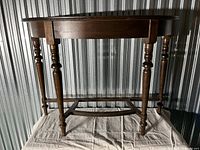 Front side view of the demi-lune table showing its half-moon shaped top and six turned legs.