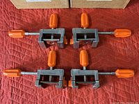 Four PONY Cabinet Claw 8510-BP clamps laid out on red fabric, showing metal bodies with orange handles.