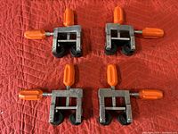 Four PONY Cabinet Claw clamps arranged on a red padded surface showing metal frames with orange handles and black rollers.