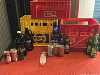 Wide angle showing overall soda and beer collection with crates, bottles, cans and thermometer