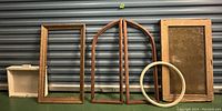 Various wood frames and cabinet doors arranged against a metal shutter backdrop exhibiting condition and details for salvage lot