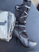 Side view of a black knee-high Bandit Boot featuring stiletto heel and leather straps, showing boot details and condition.
