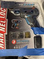 Boxed Powerforce Rapid Fire battery drill kit showing the tool and spots for cartridges with blue tape on portions of packaging.