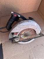 Front angle view of a Skilsaw circular saw showing the worn paint on handle and metal blade guard with rust.