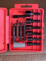 Red plastic case open showing an assortment of 12 screwdriver and nut driver bits neatly held in molded slots.