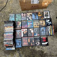 Photo of all DVD movies laid out on the ground with some stacked showing variety of titles and genres.