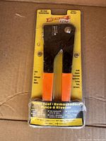 Front view of Arrow E-Z Pull Rivet Tool RL100 in original sealed packaging showing black and orange tool with product details and size compatibility.