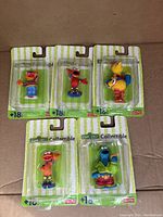 Five Sesame Street collectible Fisher Price mini figures in original blister pack packaging on green-striped backing card.