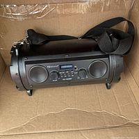 Full front view of the IQSound IQ-1525BT Bluetooth speaker showing the speaker grills, control panel, and shoulder strap.