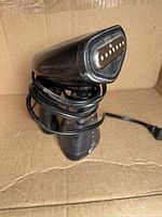 Front angled view of the handheld garment steamer with cord wrapped around it, showing metal steam plate and main body.