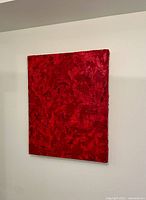 Photo of the textured red abstract painting on thick gallery-style canvas, showing front view of artwork hanging on a white wall.