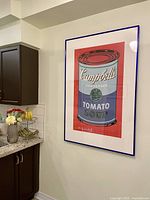 Front view of framed print hanging on wall next to kitchen cabinets