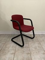 Front-right angled view of a burgundy post modern chair with tubular black metal frame.