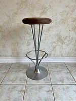 Front view of stool showing round leather seat and aluminum trumpet base.
