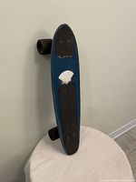 Front view of blue vintage fibreglass skateboard displaying top with black grip pads and worn white patch between them.