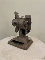 Full side view showing the base, ventilation fins, lens assembly, and film feed mechanism of the vintage Revere 8mm projector.