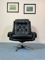 Front view of vintage black vinyl swivel rocker chair showing button tufted back and cushioned armrests.