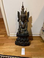 Full front view of seated Buddha statue on floor against wall